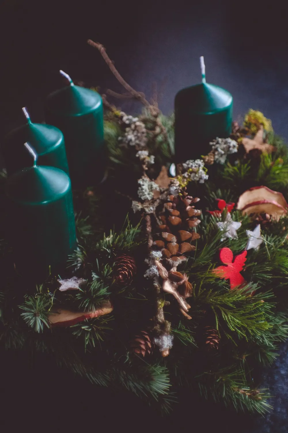 Elegant Christmas wreath with green candles and festive decorations, perfect for holiday ambiance.