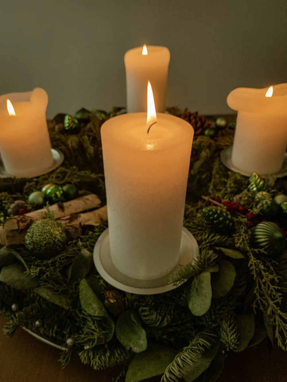 Elegant candle arrangement with festive greenery, perfect for a warm holiday ambiance indoors.
