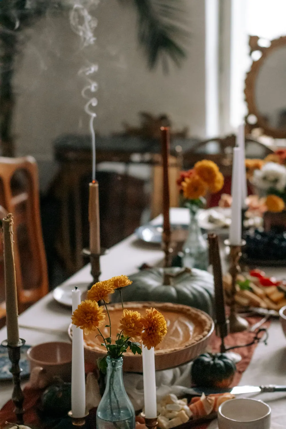 Warm and inviting autumn table setting featuring pumpkins, candles, and fall flowers.
